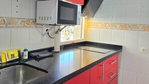 Eine Küche mit Mikrowelle, Spüle und roten Schränken.