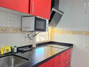 Eine Küche mit Mikrowelle, Spüle und roten Schränken.