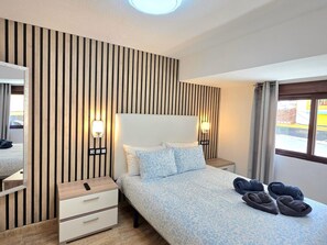 A hotel room with a bed, bedside tables, a mirror, and a window with curtains. - Central apartment with pool - 4 guests (Torremolinos)