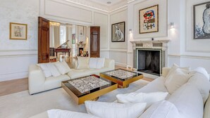 A spacious living room with a piano, sofas, and a fireplace. - Luxury London Six-Bedroom House in Marylebone - Moments from Regent’s  Park (London)