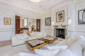 A spacious living room with a piano, sofas, and a fireplace. - Luxury London Six-Bedroom House in Marylebone - Moments from Regent’s  Park (London)