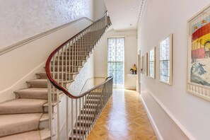 A staircase with a wooden handrail and beige carpeted steps leading to a door with a glass panel.