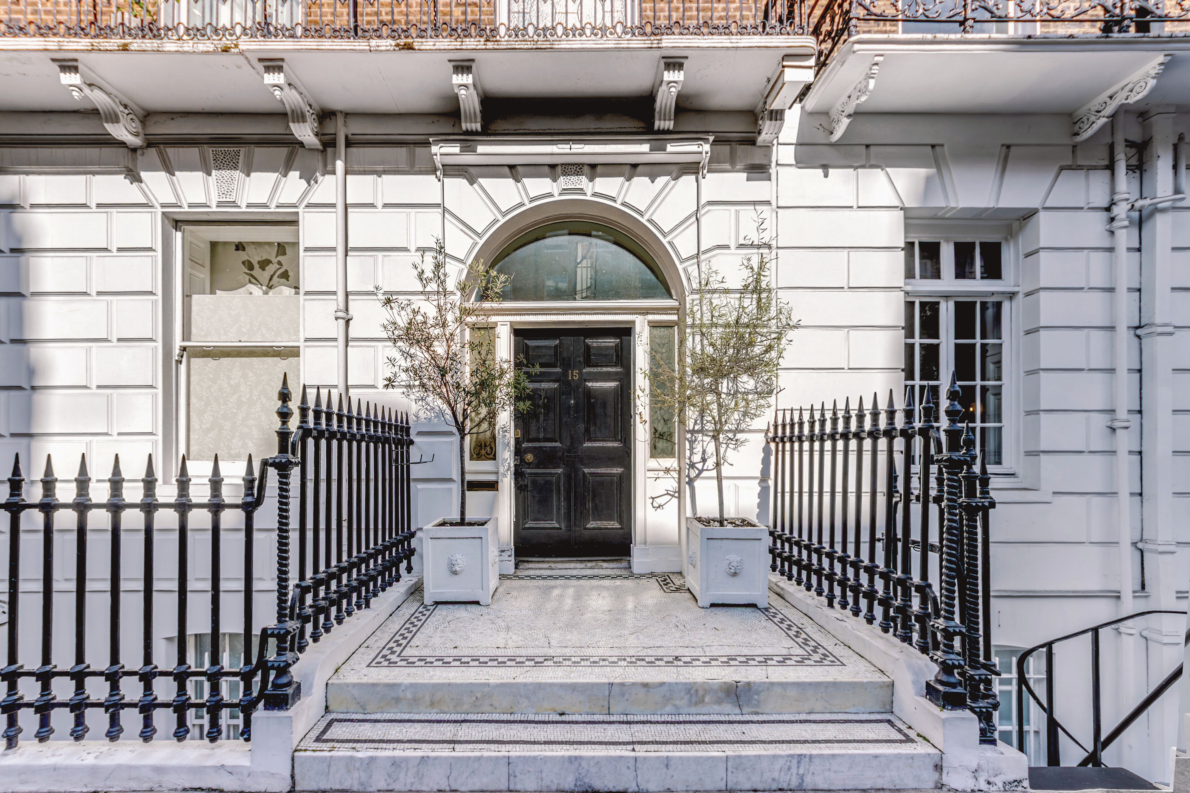 A building facade with a black door, white trim, and a symmetrical black iron fence.