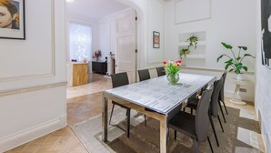 A dining room with a glass table, chairs, and a vase with flowers. - Luxury London Six-Bedroom House in Marylebone - Moments from Regent’s  Park (London)