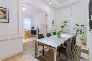 A dining room with a glass table, chairs, and a vase with flowers. - Luxury London Six-Bedroom House in Marylebone - Moments from Regent’s  Park (London)