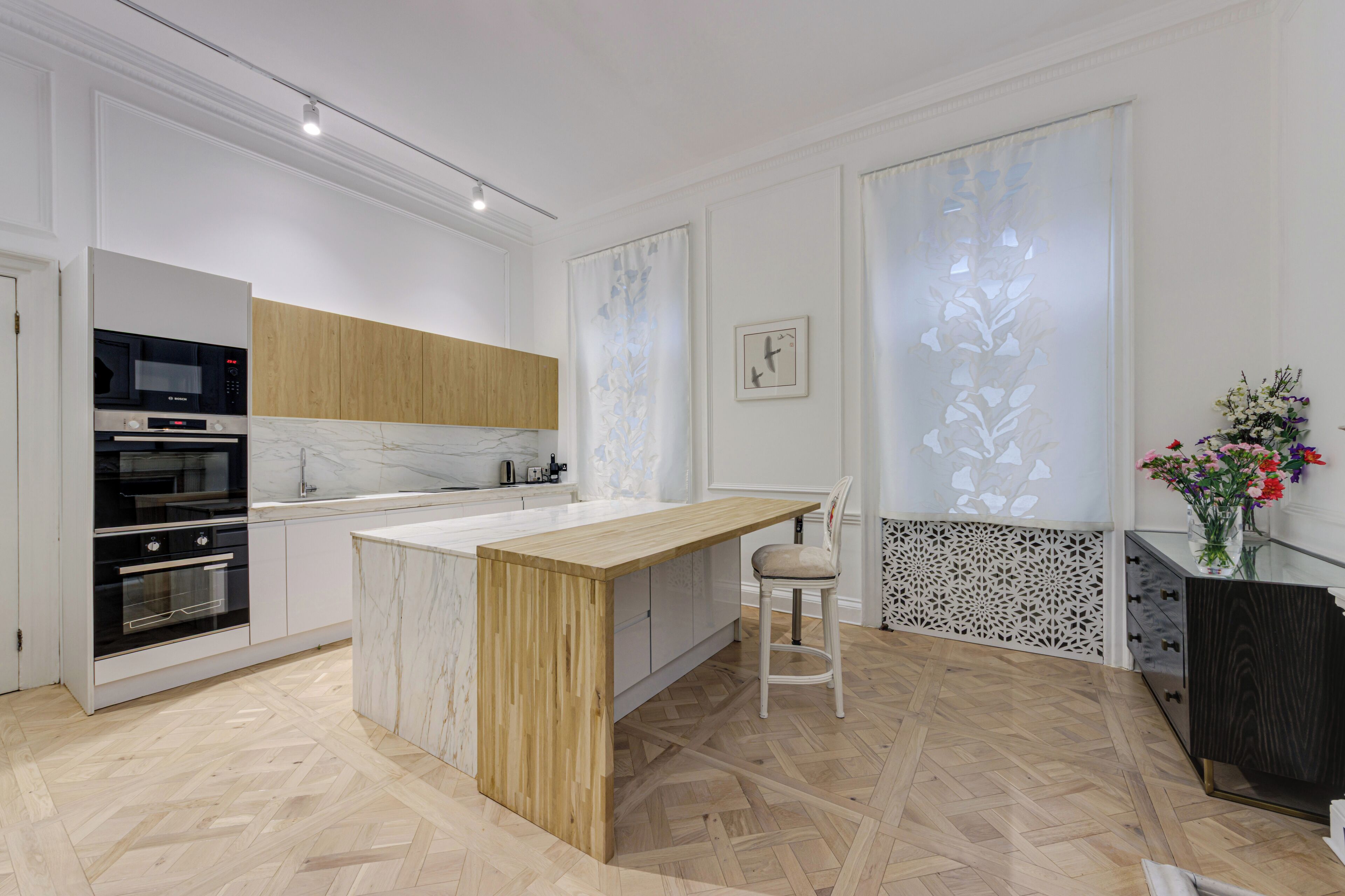 A modern kitchen with a marble countertop, wooden cabinets, and a built-in oven.