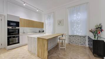 A modern kitchen with a marble countertop, wooden cabinets, and a built-in oven.