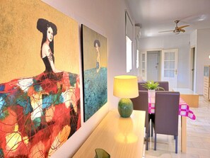 Ein Essbereich mit Tisch, Stühlen und einer Lampe. An der Wand befinden sich Gemälde.