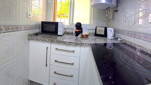 Eine Küche mit weißen Schränken, einer Mikrowelle, einem Toaster und einer Kaffeemaschine auf der Arbeitsfläche.