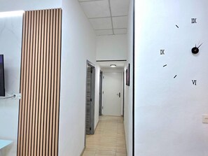 Ein Flur mit Wandverkleidung aus Holz, einer Uhr und einer Tür am Ende.