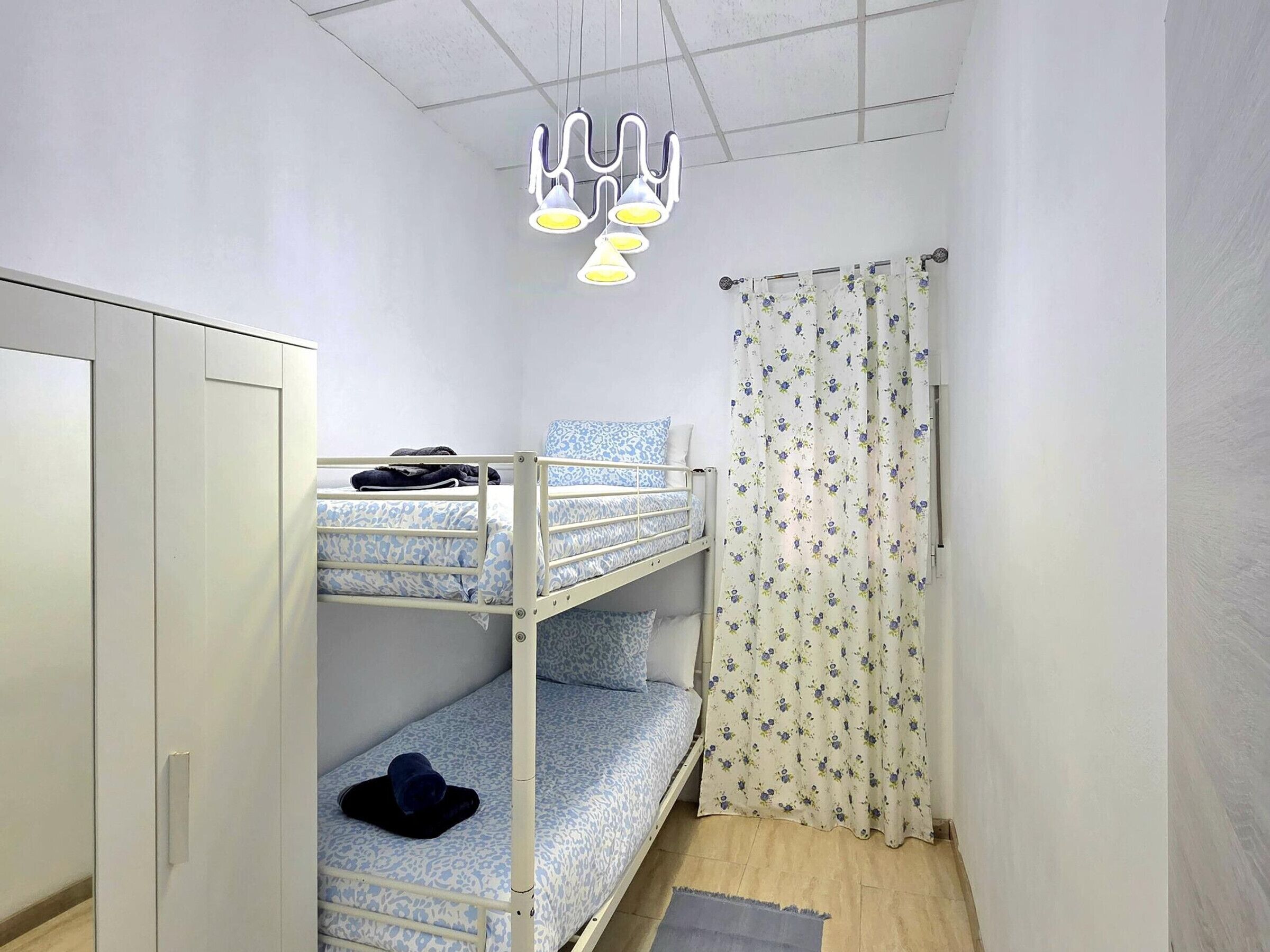 A bunk bed room with a wardrobe, a curtain, and a hanging light fixture.