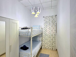 Ein Schlafraum mit Etagenbett, Kleiderschrank, Vorhang und Pendelleuchte.