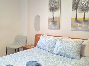 Ein Hotelzimmer mit einem Bett, einem Sessel und zwei Bildern an der Wand.