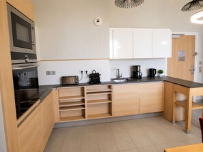Eine moderne Küche mit eingebauten Geräten, Holzschränken und einer Arbeitsplatte mit Kaffeemaschine und Toaster.