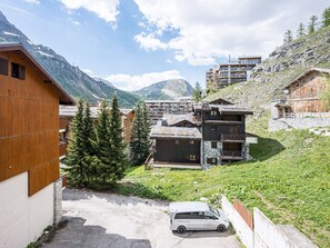 Ein Berggasthof mit Holzfassade, ein Steinhaus und ein Auto davor.