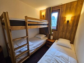 A bunk bed room with a window, a bedside lamp, and a wooden wall. - Cozy studio with cabin - 4 guests (Val-d'Isère)