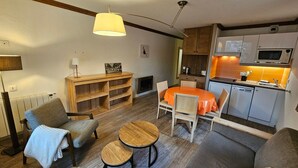 Ett kompakt bostadsutrymme med en matplats, ett litet kök och en sittgrupp.