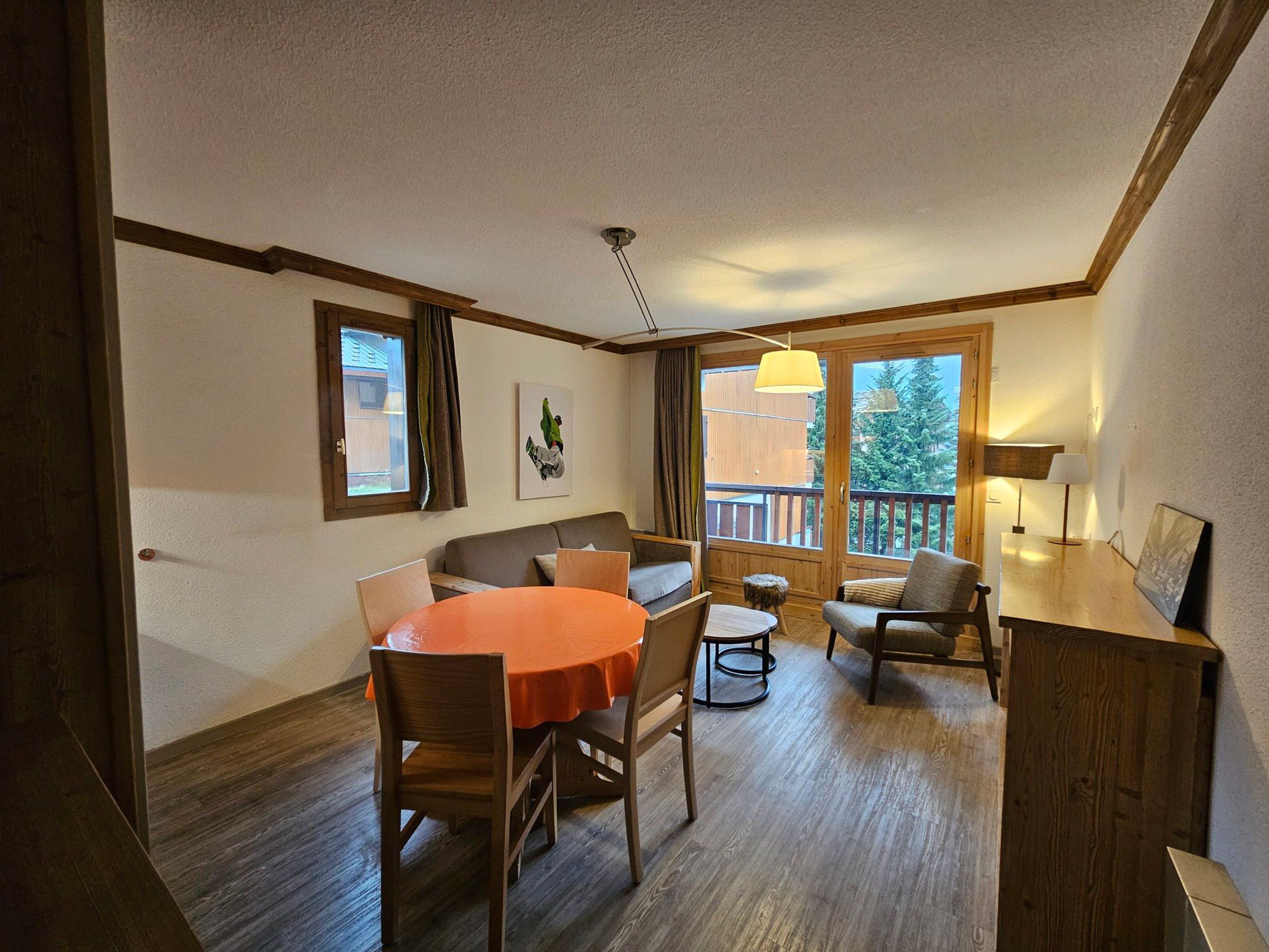 A dining area with a round table and chairs, a sofa, and a wooden cabinet.