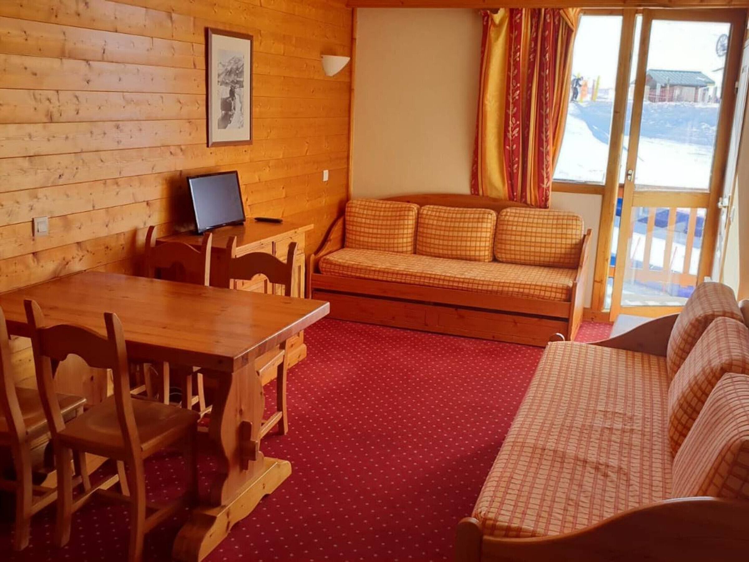 A wooden interior with a sofa, a dining table, and chairs.