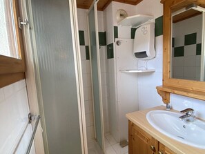 Ein Badezimmer mit Dusche, Waschbecken und Spiegel.