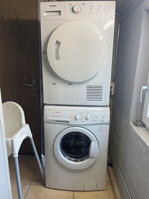 Máquina de lavar compacta, de abertura frontal, com secadora superior.