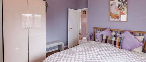 A bedroom with a bed, a wardrobe, and a door leading to another room.