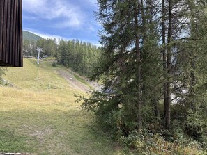 A mountainous landscape with a ski lift, dense forest, and a clear sky. - Spacious apartment at the foot of the slopes - 6 guests (Les Orres)