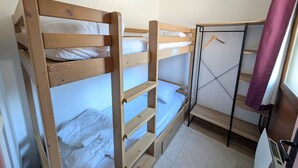 A bunk bed room with a wooden bunk bed, a metal wardrobe, and a small window with a curtain. - Renovated studio facing slopes - 3 guests (Montgenèvre)