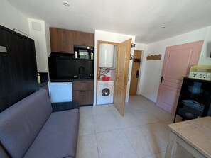 A compact living space with a kitchenette, a washing machine, a sofa, and a small table. - Renovated studio facing slopes - 3 guests (Montgenèvre)