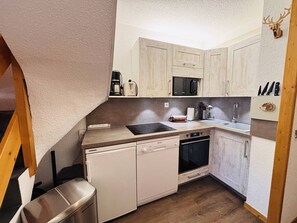A compact kitchen with white cabinets, a microwave, a sink, and a dishwasher. - Duplex apartment, balcony with pine view - 6 guests (La Plagne Tarentaise)