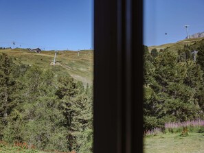 Paesaggio montuoso con una seggiovia e una funivia in lontananza.