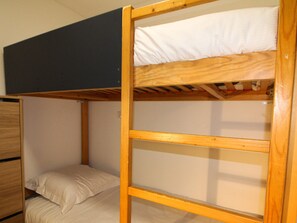 Ein Stockbett mit Holzrahmen und weißer Bettwäsche.