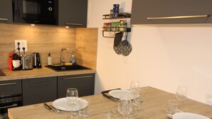 Eine moderne Küche mit Holztischplatte, integriertem Mikrowellenherd, Spüle und einem Essbereich, gedeckt mit Tellern, Gläsern und Besteck.