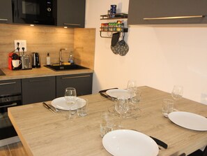 Eine moderne Küche mit Holztischplatte, integriertem Mikrowellenherd, Spüle und einem Essbereich, gedeckt mit Tellern, Gläsern und Besteck.