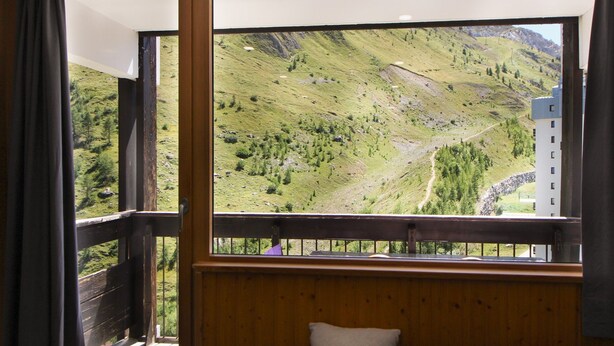 Ein Zimmer mit einem großen Fenster und Blick auf eine gebirgige Landschaft.