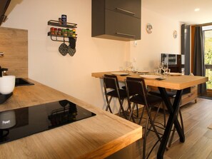 A modern kitchen with a wooden countertop, black chairs, and a dining table set for four. - Cozy apartment - 4 guests (Tignes)