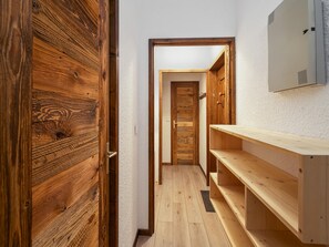 A narrow hallway with wooden doors and a wooden shelf unit. - Pleasant apartment, mountain view - 4 guests (Le Monêtier-les-Bains)