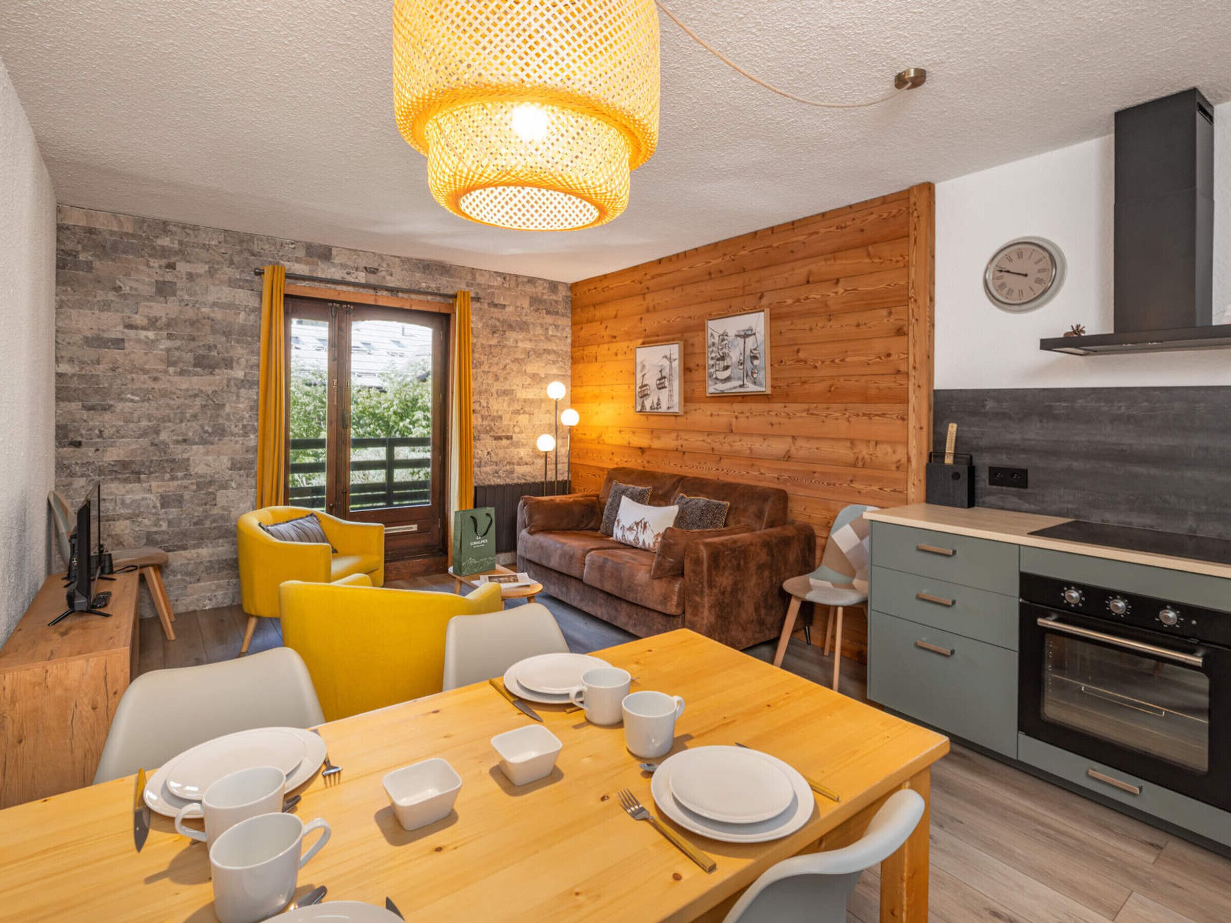 A modern kitchen with a wooden wall, a dining area with a wooden table and chairs, and a cozy seating area with a sofa and armchairs.