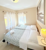 Habitación de hotel con dos camas, una mesita de noche con lámpara y un cuadro en la pared.