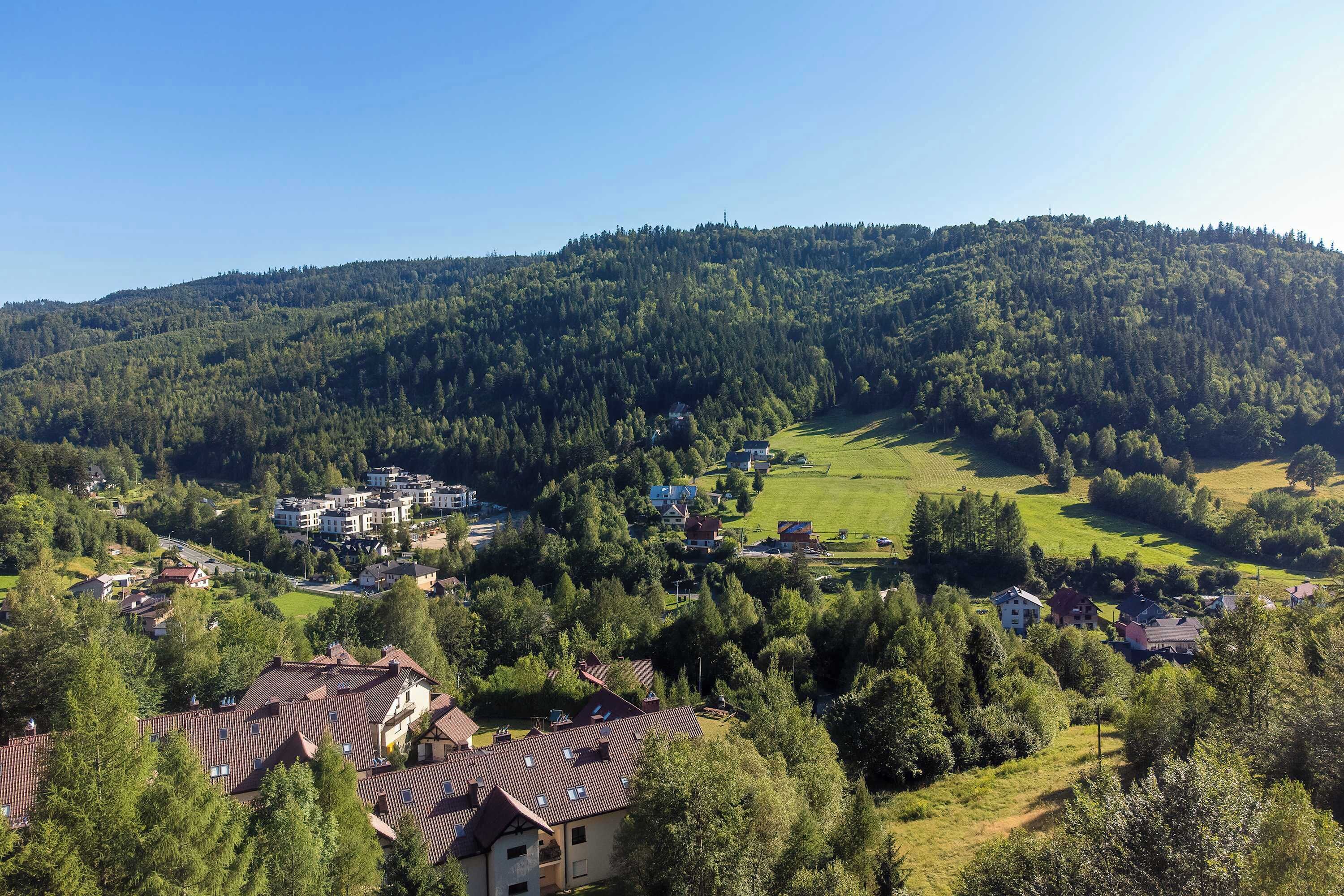 Un quartier résidentiel composé de maisons et d’un petit centre communautaire, le tout entouré de collines boisées.