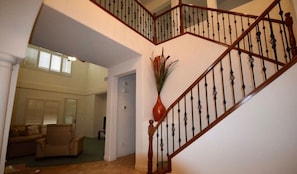 Una escalera con barandilla de madera y balaustres negros que sube a un nivel superior.