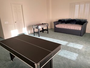 A room with a foosball table, a sofa, and a ping pong table. - Luxury 6BR Summerlin West Oasis Detached Casita Gated Community (Las Vegas)