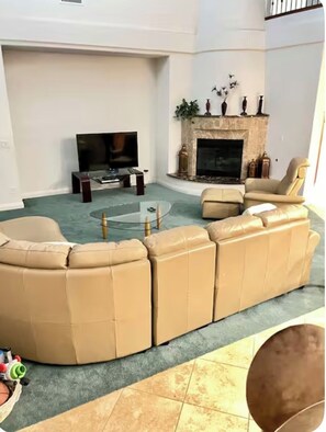 A living room with a sectional sofa, a flat-screen TV, a fireplace, and a coffee table. - Luxury 6BR Summerlin West Oasis Detached Casita Gated Community (Las Vegas)