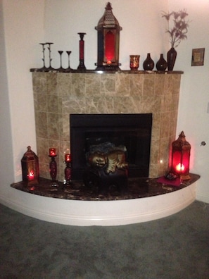 Una chimenea con repisa de piedra, rodeada de velas y adornos.