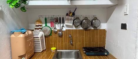 A compact kitchen with a sink, stove, and various utensils.
