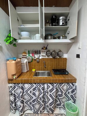 A compact kitchen with a sink, stove, and various utensils. - Ian's Place (Bacolod)