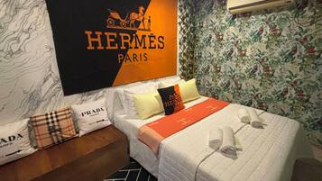 Habitación de hotel con cama, almohadas, aire acondicionado de pared y papel tapiz floral.