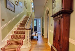 A grand staircase with ornate railings and patterned carpet leading to a door.