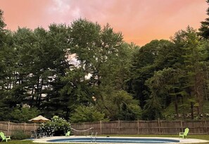 Un pati d'entrada amb una piscina, envoltat per una tanca de fusta i arbres.