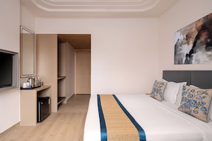 Une chambre d’hôtel équipée d’un lit, d’une télévision, d’une machine à café et d’une porte donnant sur un couloir.